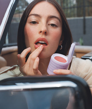 woman in a car applying her makeup stack