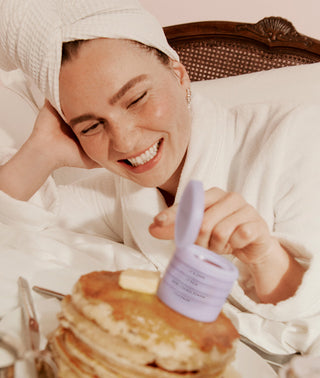 woman in a robe in a hotel with her makeup stack on a stack of pancakes