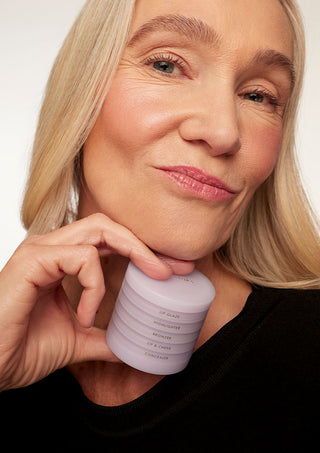 mature woman posing with her makeup stack in her hand