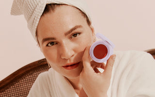 woman in a bathrobe in a hotel taking a photo with a makeup stack layer