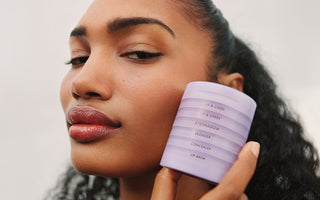 woman holding the makeup stack by her face wearing lip glaze