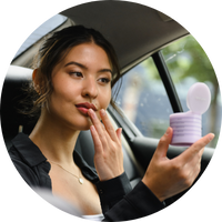 woman applying her makeup stak in the back of a car